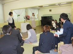入園式で保育士の出し物を親子で見ている写真