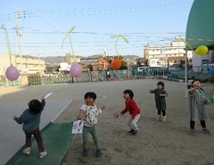 ３歳児が風船で羽根つきをしている写真
