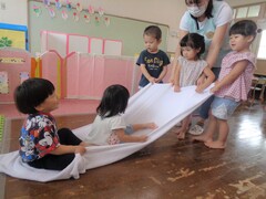 室内でバスタオルを使って運動遊びをしている写真