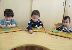 ０歳児がクリスマスの飾りを作っている写真
