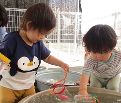 ０歳児がペットボトルで作ったシャワーで遊んでいる写真
