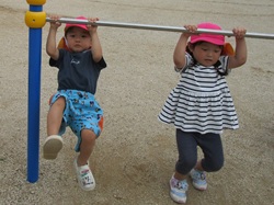 2歳児が鉄棒にぶら下がって遊んでいる写真