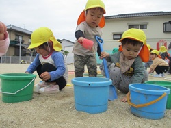 2歳児が砂遊びをしている写真