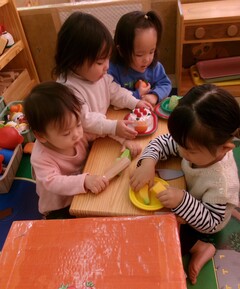 １歳児が室内でごっこ遊びをしている写真