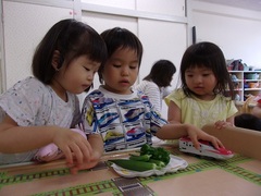2歳児が収穫したオクラとピーマンを一緒に見ている写真