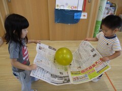 新聞紙で風船を運んで遊んでいる写真