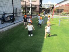 芝生の園庭を元気に駆ける子どもたち
