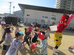 鬼の持っているカゴに豆を投げ入れる子どもたちの写真