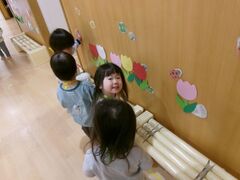 壁に貼られた春の飾りを指して見ている写真