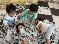 新聞紙で遊ぶ子どもたちの写真