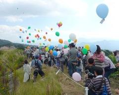 葉佐池（　はざいけ）古墳レンゲソウまつりのプレイベントでメッセージを風船に付けて大空へ飛ばしています